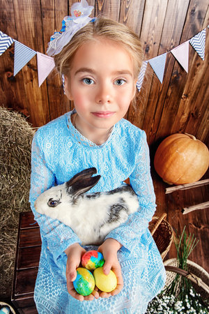 Easter holidays. Happy little child girl holds Easter Bunny and painted eggs and smiling.