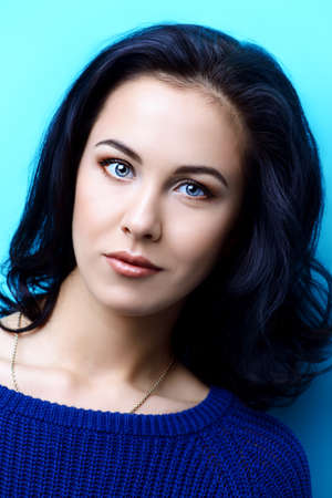 Portrait of a beautiful young woman with brunette hair over bright blue background. Beauty, fashion concept. Cosmetics, make-up. Copy space.の写真素材