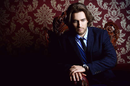 Fashionable male model in elegant formal suit posing in apartments with classical vintage interior.の写真素材