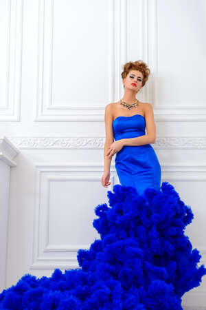 Full length portrait of a stunning young woman wearing luxurious long dress and jewellery. Luxury, rich lifestyle. Jewellery. Fashion shot. Interior in classical style.の写真素材