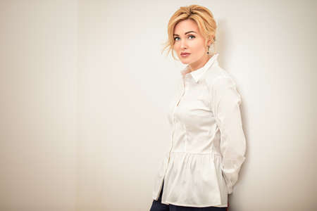 Portrait of a beautiful middle-aged woman in white blouse. Elegant businesswoman in the office.の写真素材