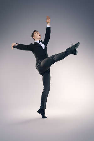 Elegant young man dancer in black suit and bow-tie posing at studio. Male ballet dancer.の写真素材