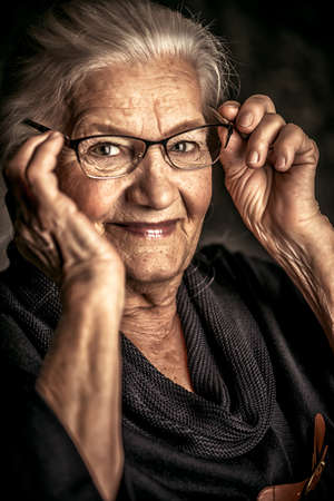 Portrait of a beautiful senior woman in elegant glasses smiling at camera.の写真素材