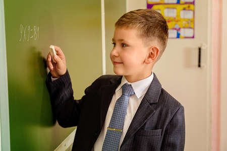 A schoolboy in uniform writing on a blackboard. Educational concept.の写真素材