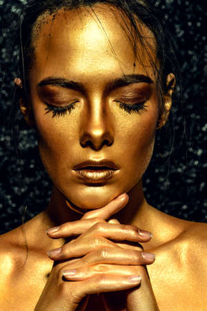 Beauty concept. Close-up portrait of a beautiful young woman with glowing golden skin. Skin care products, cosmetics. Jewellery concept.の写真素材