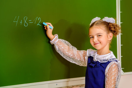 A schoolgirl in uniform writing on a blackboard.
