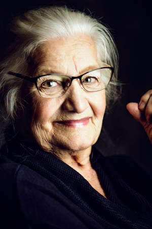 Portrait of a beautiful senior woman in elegant glasses smiling at camera.の写真素材
