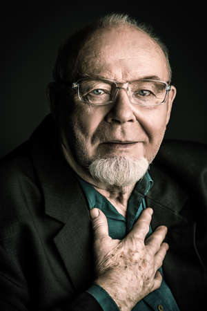 Portrait of a smiling old man over black backgroundの写真素材