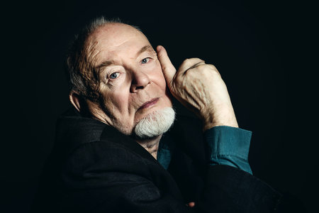 Portrait of old man over black background.