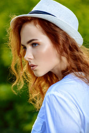 Pretty redhead girl in white summer clothed standing outdoor. Summer day.の写真素材