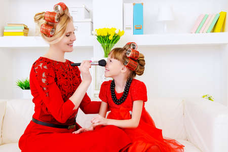 Happy mother with her lovely daughter preparing for the holiday, doing hairstyles and makeup. Happy family concept. Beauty, fashion.の写真素材