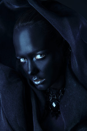 Beautiful young woman with perfect black skin and silver glitter lips wearing beautiful necklace and black veil. Cosmetics and make-up. Jewelry and bijouterie. Body painting project. African style.の写真素材