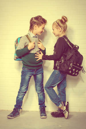 Children's fashion. Modern boy and girl posing together at studio. Education.の写真素材
