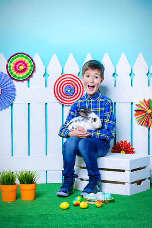 Happy child boy with Easter Bunny and painted eggs in spring decorations. Kid's fashion. Easter holidays.の写真素材