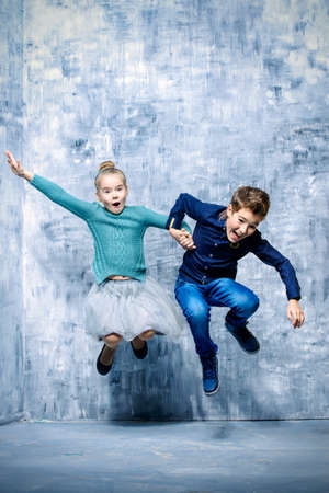 Kid's fashion. Two laughing children jumping for joy. Studio shot. Clothes for children.の写真素材