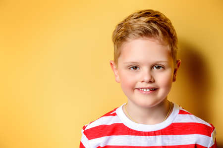 Portrait of a cute boy over bright yellow background. Clothes for children. Kid's fashion.の写真素材
