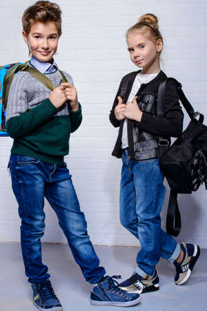 Children's fashion. Modern boy and girl posing together at studio. Education.の写真素材