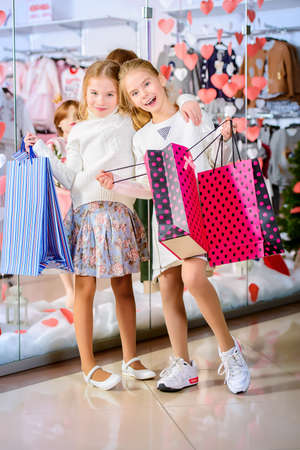 Two cute little girls go shopping. Kid's fashion. Modern children. Seasonal sale, shopping.の写真素材