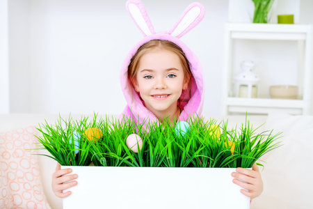 Easter holidays. Funny happy little girl wearing bunny ears celebrating Easter at home.