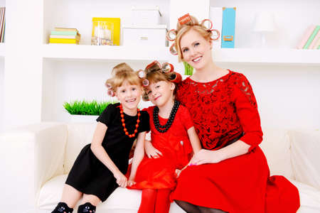 Happy mother with two daughters preparing for the holiday, doing hairstyles and makeup. Family concept. Beauty, fashion.の写真素材