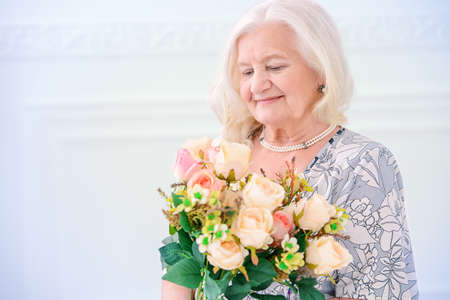 Beautiful senior woman at home with a bouquet of flowers. Happy Mother's Day. Beauty, fashion. Happy retirement.の写真素材