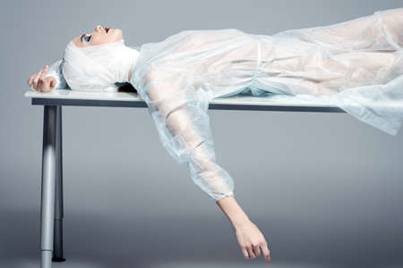 Beauty, fashion and medicine, plastic surgery. Portrait of an attractive young woman in bandages and hospital gown lying on the operating table.の写真素材