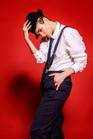 Attractive young model posing in a man's shirt and trousers with suspenders.の写真素材