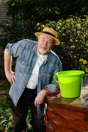 Portrait of a happy senior man standing in his garden on a sunny summer day.の写真素材