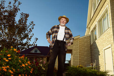 Happy retired senior man,  full of health, standing in his garden near the house. Sunny summer day.の写真素材