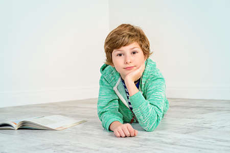 Pretty happy nine-year girl lying on a floor and smiling. Children's fashion. Education. Activity and child concept. Copy space.の写真素材