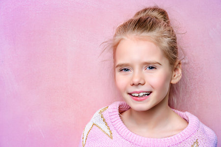 Portrait of a happy smiling girl over pink background.