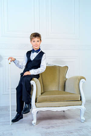 Handsome nine year old boy in elegant suit posing in luxurious apartments. Kid's fashion.の写真素材