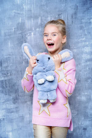 Kid's fashion. Portrait of a laughing little girl with a bag like a fluffy bunny.の写真素材