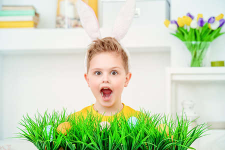 Easter holidays. Funny happy boy wearing bunny ears celebrating Easter at home.の写真素材