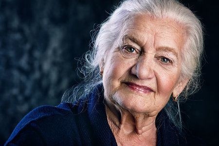 Portrait of a beautiful smiling senior woman over dark background.