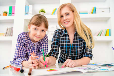 Happy family at home. Mother and daughter drawing and do lessons together. Education.の写真素材