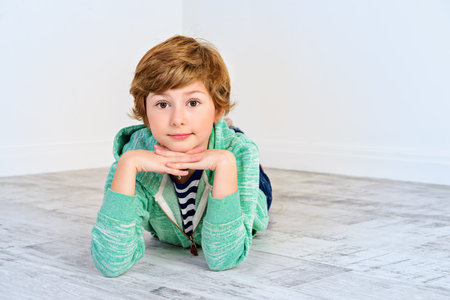 Pretty happy nine-year girl lying on a floor and smiling. Children's fashion. Education. Activity...