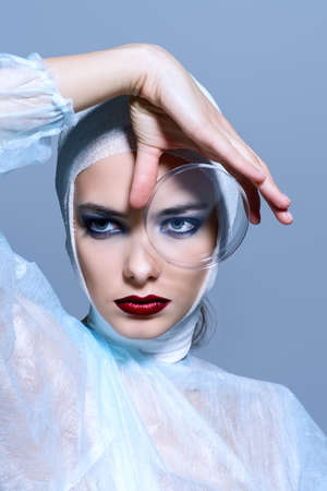 Close-up portrait of an attractive young woman in bandages holding a Petri dish. Beauty, fashion and medicine, plastic surgery. Studio shot.の写真素材