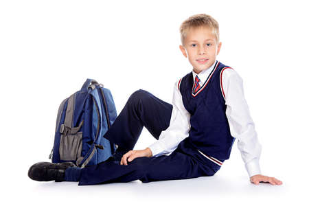 Full length portrait of a cute smiling nine year old boy in a school uniform and school bag. Educational concept. Children's fashion. Isolated over white background. Copy space.の写真素材