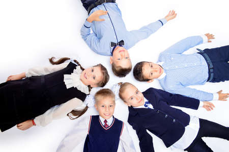 Group of happy school children posing together at studio. School uniform. Educational concept. Isolated over white.の写真素材