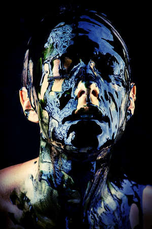 Beauty provocation. Body painting project. Portrait of a young woman with golden skin and black oil pouring on her. Fashionable provocation. Pollution and poisoning concept.の写真素材