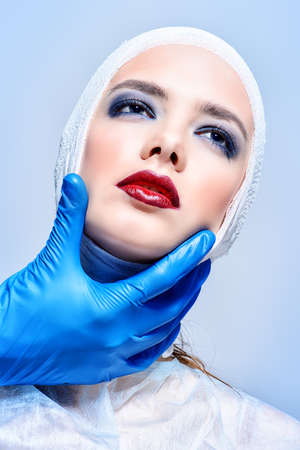 Beauty, fashion and medicine, plastic surgery. Portrait of an attractive young woman in bandages and hospital gown. Studio shot.の写真素材