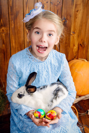 Easter holidays. Happy little child girl holds Easter Bunny and painted eggs and laughing.