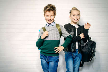 Children's fashion. Modern boy and girl posing together at studio. Education.の写真素材