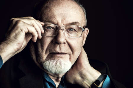 Portrait of the old man wearing spectacles. Black background. Old age concept.の写真素材