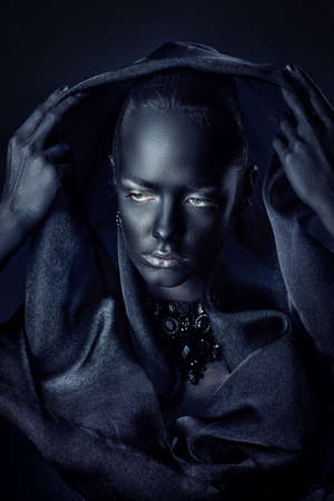 Beautiful young woman with perfect black skin and silver glitter lips wearing beautiful necklace and black veil. Cosmetics and make-up. Jewelry and bijouterie. Body painting project. African style.の写真素材