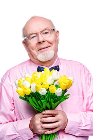 Happy smiling old man gives a bouquet of tulips flowers. Women's Day, 8 of March, birthday concept. Retirement. Isolated over white.の写真素材