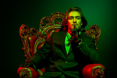 Handsome man in an expensive suit and black leather gloves sitting in a classical vintage armchair....