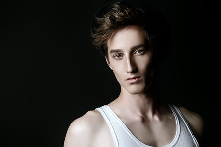Portrait of a sexy muscular young man over black background. Men's beauty, fashion.