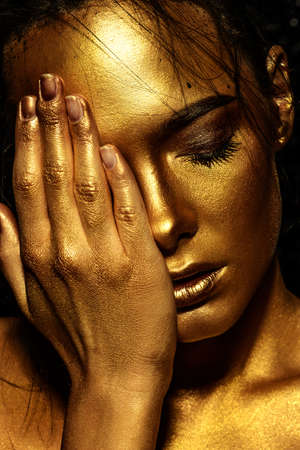 Beauty concept. Close-up portrait of a beautiful young woman with glowing golden skin. Skin care products, cosmetics. Jewellery concept.の写真素材